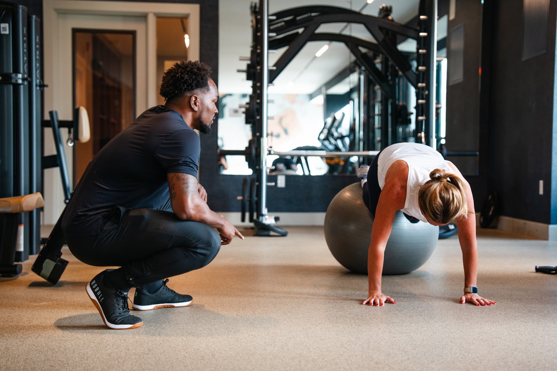 A trainer coaching a client through a stability-ball push-up in a residential gym