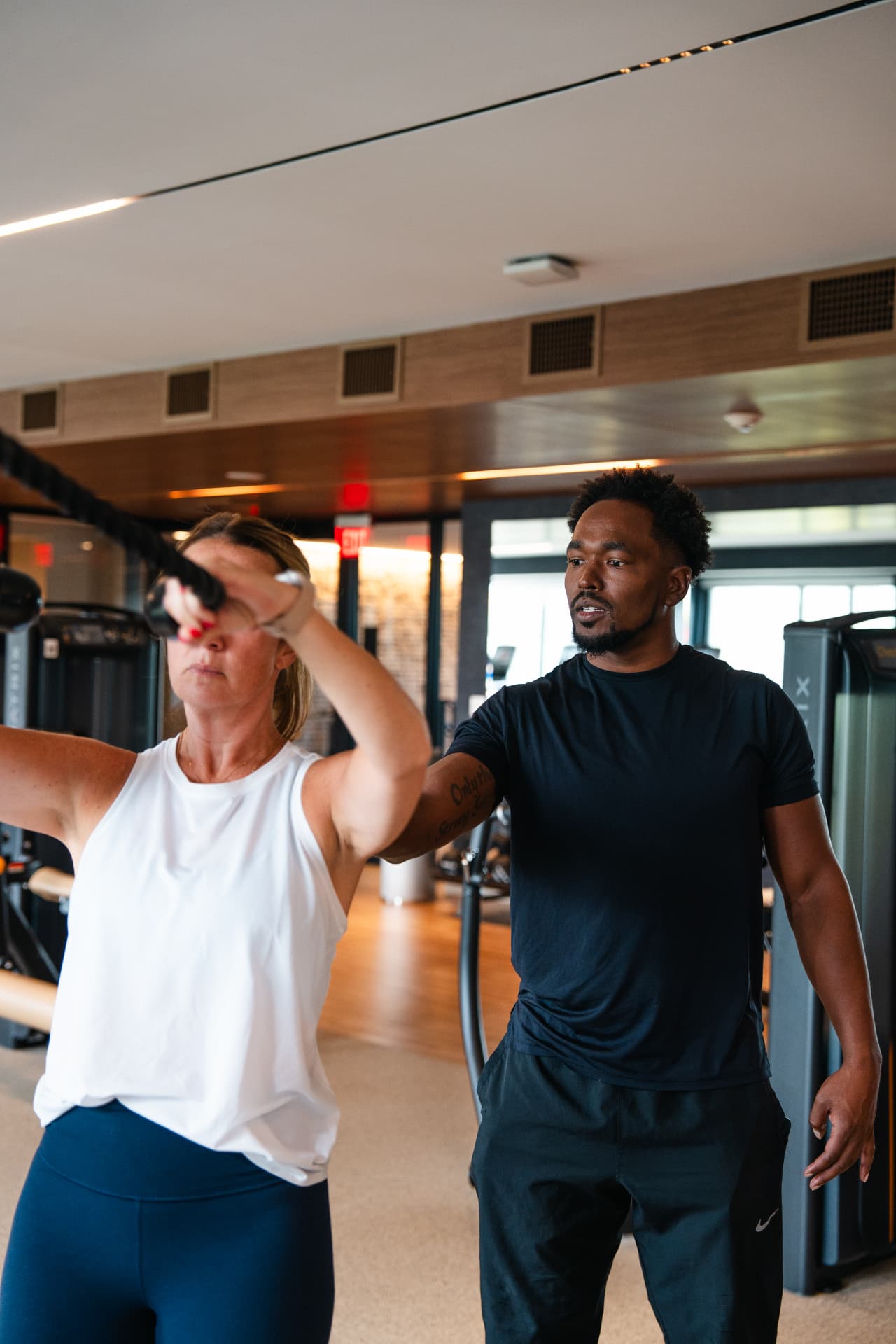 A personal trainer coaching a client through a cable exercise in a gym