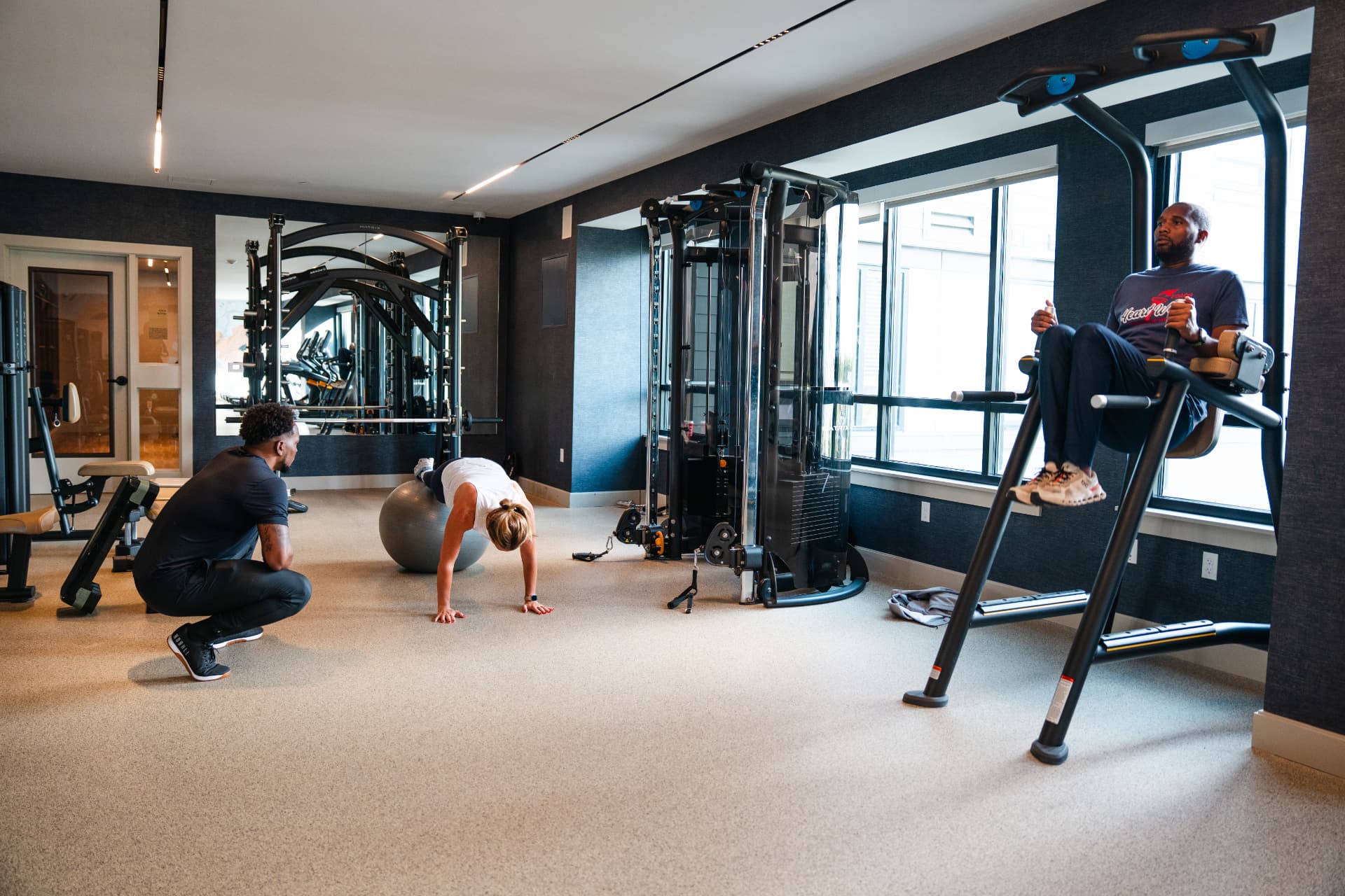 A PerryPerformFit trainer coaching clients in a residential building gym