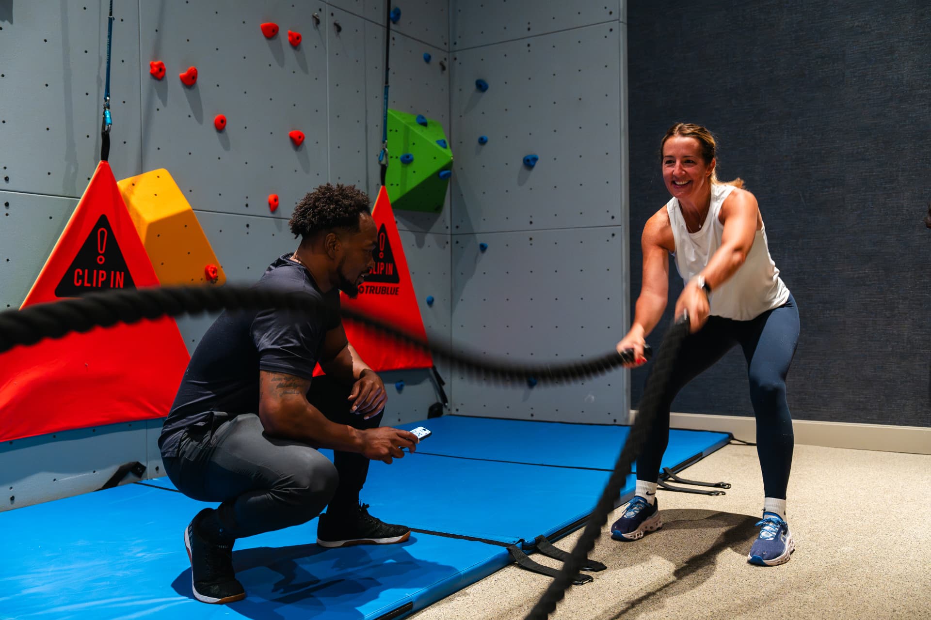 A trainer coaching a client through a battle rope session